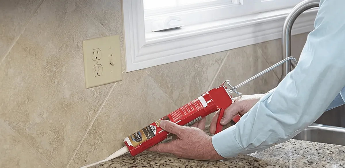 Handyman applying caulk along a kitchen backsplash and countertop seam in San Antonio, TX